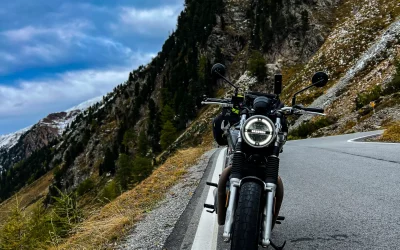 Motocicleta aparcada en carretera de montaña con árboles y cielo nublado